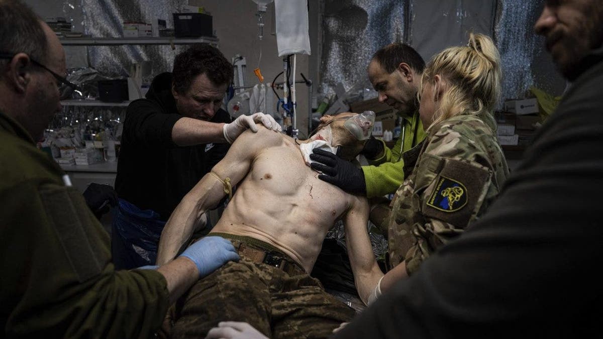 shirtless Ukrainian soldier being tended to by medics