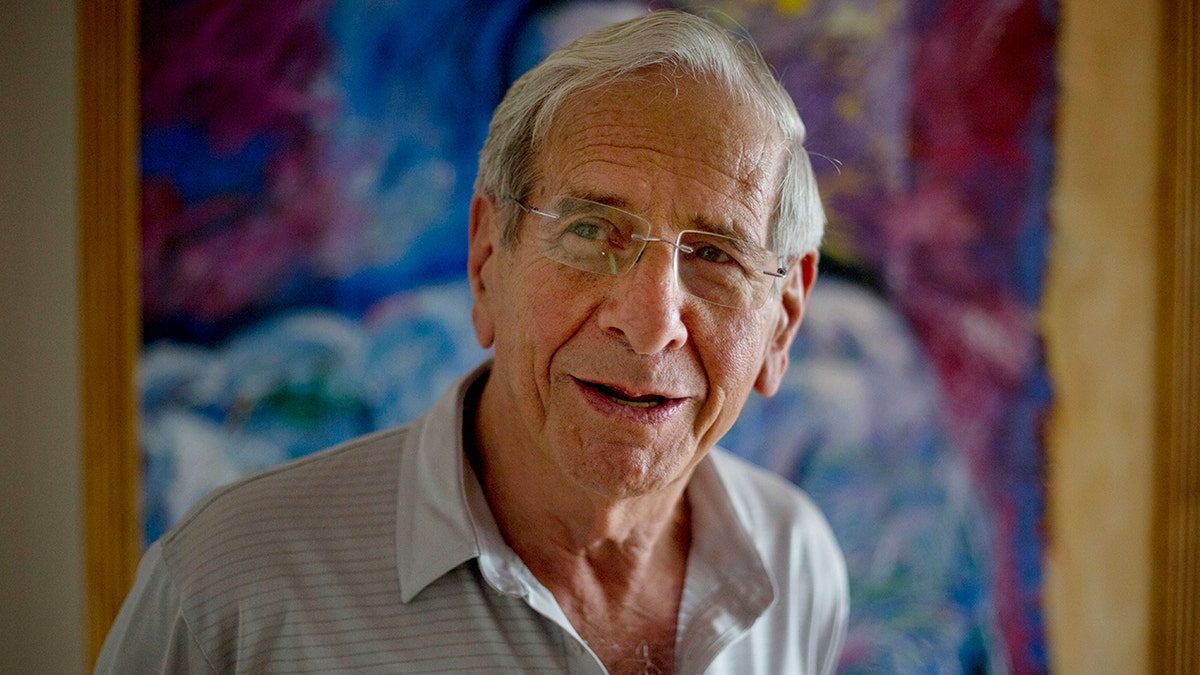 Chaim Topol wearing a button down shirt and transparent glasses looks off camera in an interview given in 2015