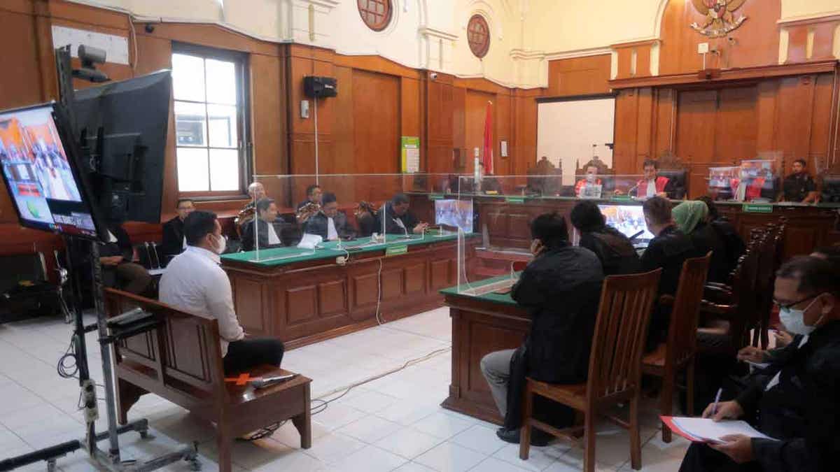 Police officer Hasdarmawan, left, sits on the defendant's chair during his sentencing hearing at a district court in Surabaya, Indonesia, on March 16, 2023. The Indonesian court sentenced Hasdarmawan to 18 months in prison for negligence leading to the deaths of 135 people in October. Other officers who played less of a role in the incident were acquitted in court.