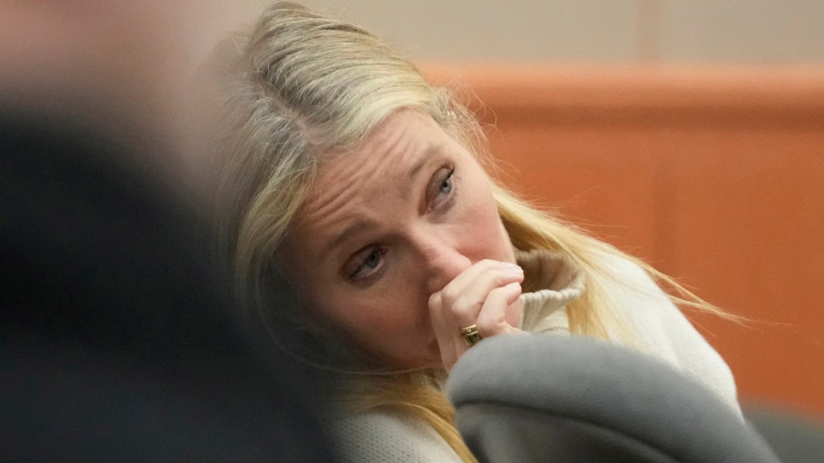 Gwyneth Paltrow puts her hand to her nose, covering her mouth as she looks on in court 