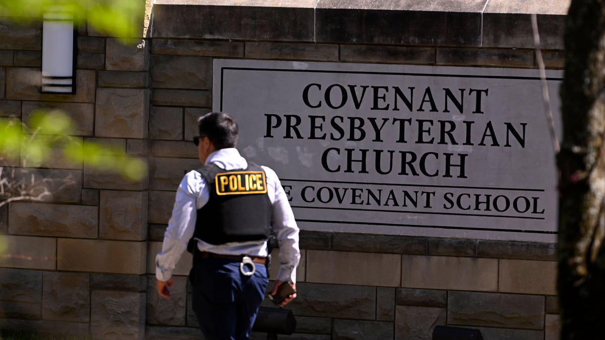 A police officer walks by an entrance to The Covenant School after a shooting in Nashville, Tennessee, Monday, March 27, 2023.