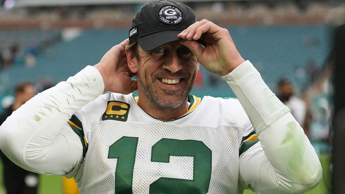 Aaron Rodgers adjusts his cap