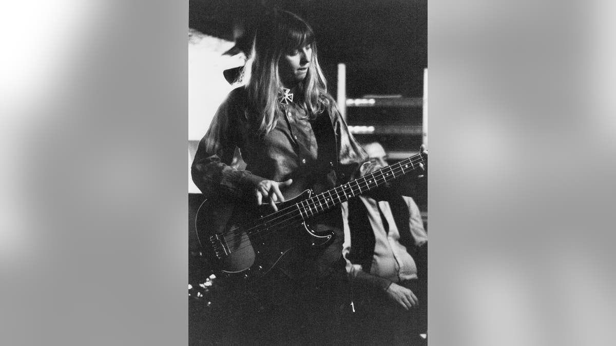 A black and white photo of Bebe Buell playing guitar