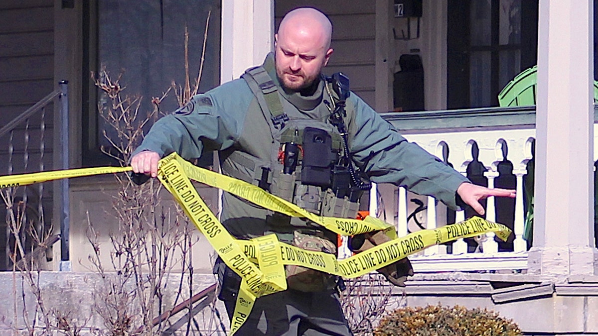 Officer unrolls police tape