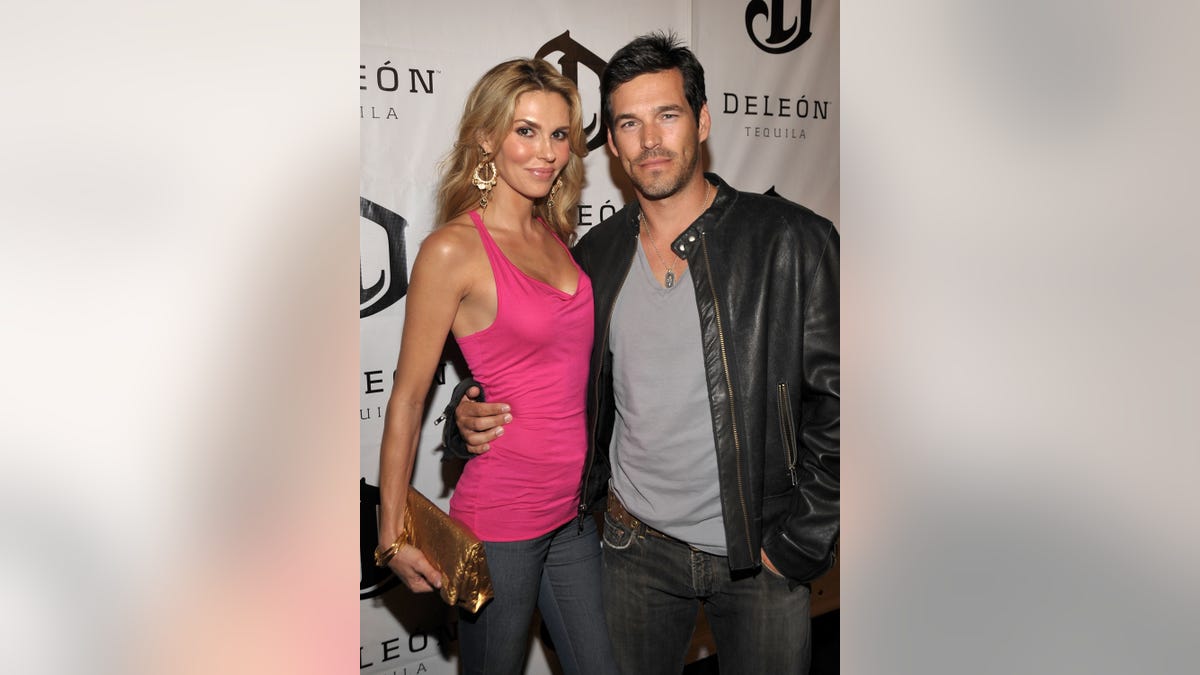 Brandi Glanville wears pink top and jeans with Eddie Cibrian on red carpet