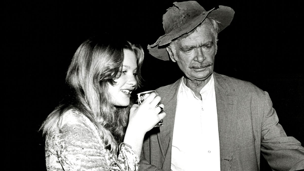 Kiki Ebsen drinking from a soda can while talking to her father Buddy Ebsen in costume