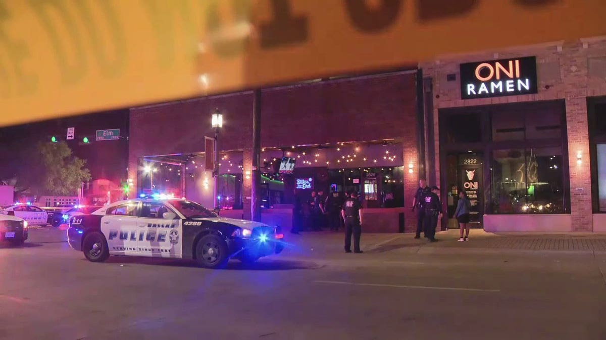 Police standing outside of building at a crime scene.