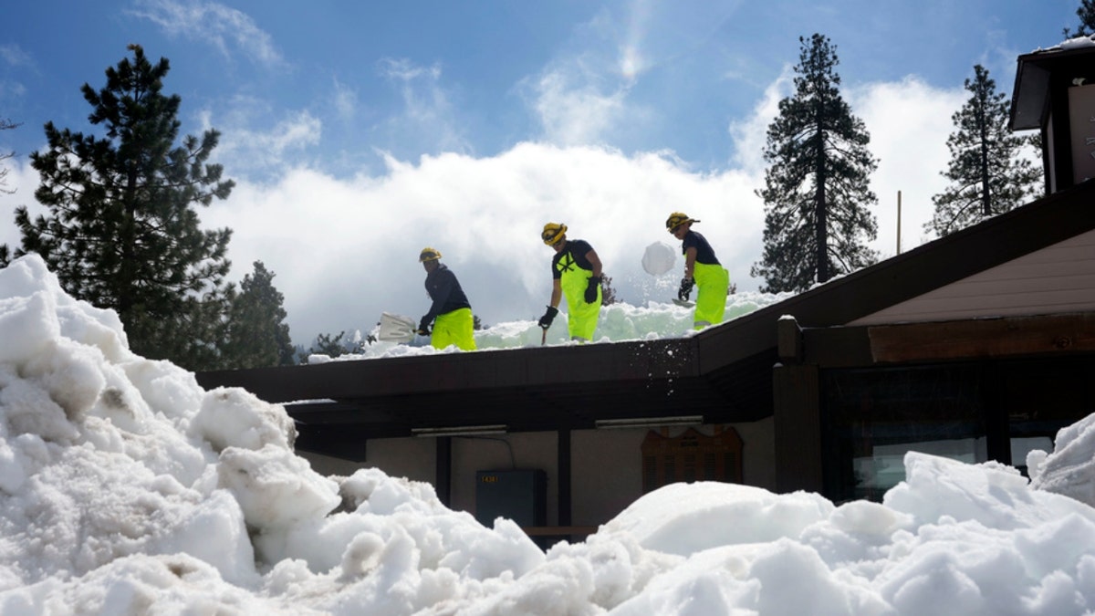 A Cal Fire crew clears snow off a roof