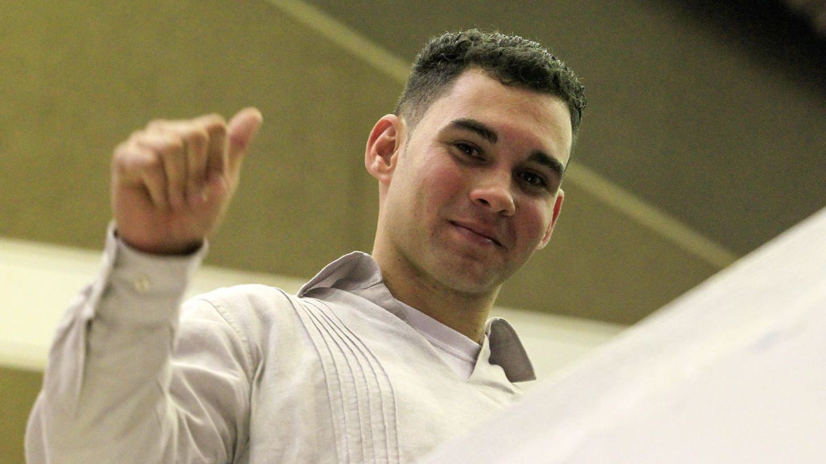 Elian Gonzalez smiled and holds his hand up