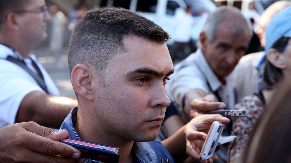 Elian Gonzales flanked by reporters