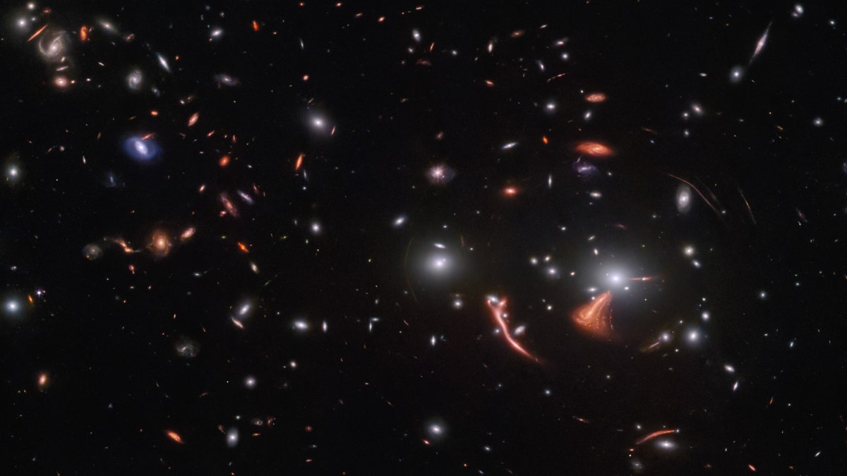 Small galaxies on a black background, some distorted by gravitational lensing