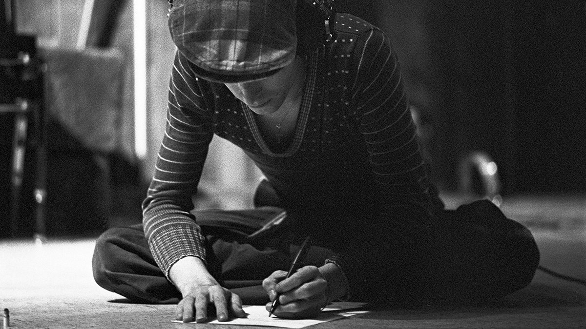 David Bowie writing song lyrics in a black and white photo
