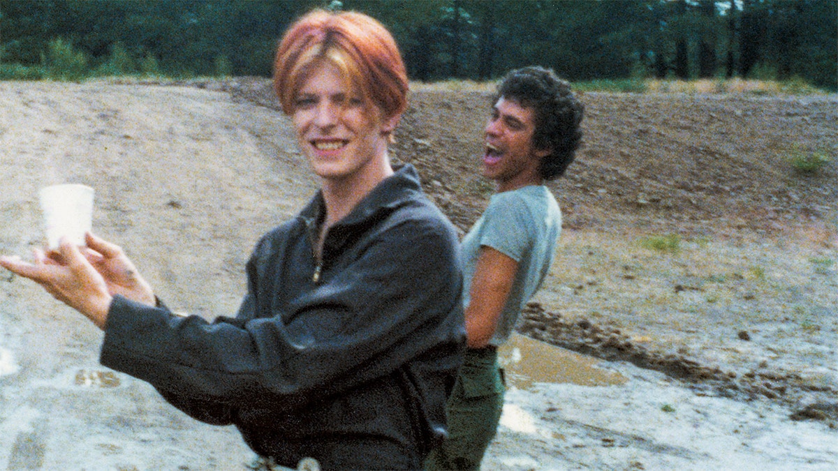 David Bowie and Geoff MacCormack joking around outdoors