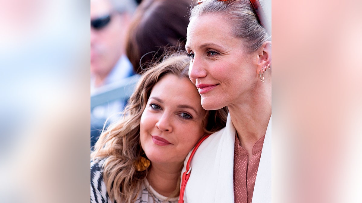 Drew Barrymore leans her head against the shoulder of friend Cameron Diaz wearing a white blazer at Lucy Liu's Walk of Fame ceremony