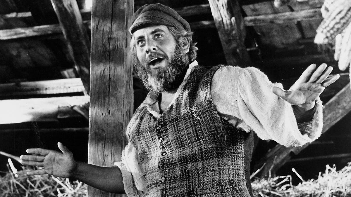 Chaim Topol in a black and white photo wears a cap and tweed vest as Tevye the Dairyman in 'Fidder on the Roof'