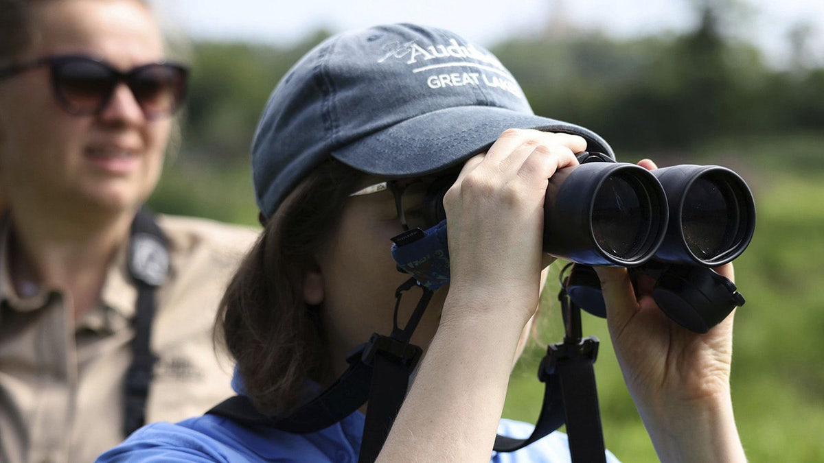 Woman looks through binoculars for birds