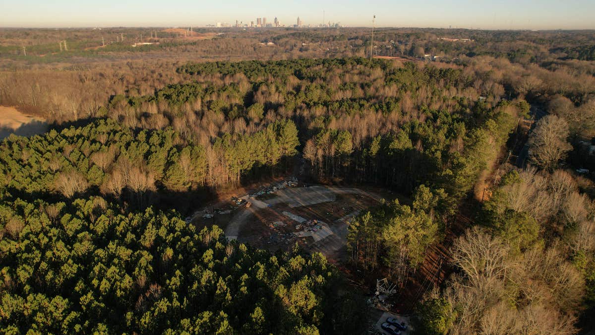 aerial view of law enforcement vehicles block the entrance to the planned site of a police training facility 