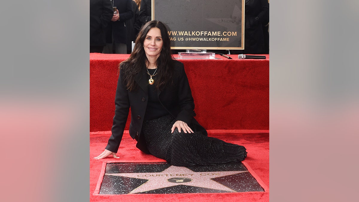Courteney Cox lies on the red carpet in an all-black outfit as she receives her star on the Hollywood Walk of Fame