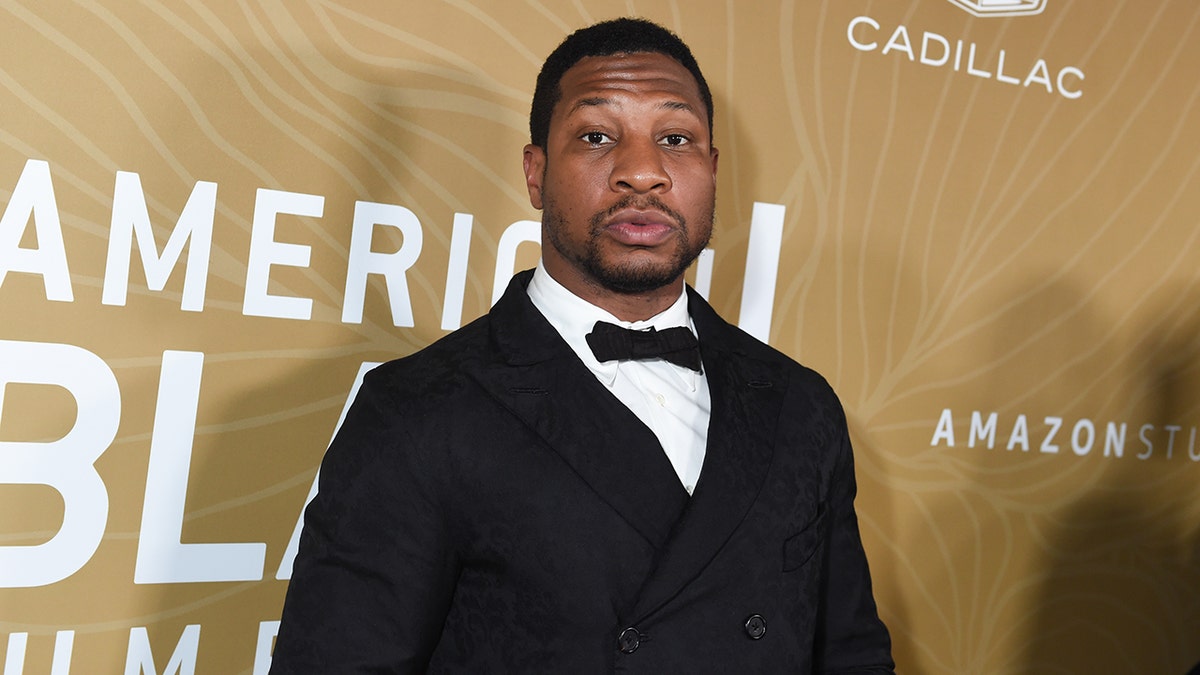 Jonathan Majors looks at camera in classic tuxedo 