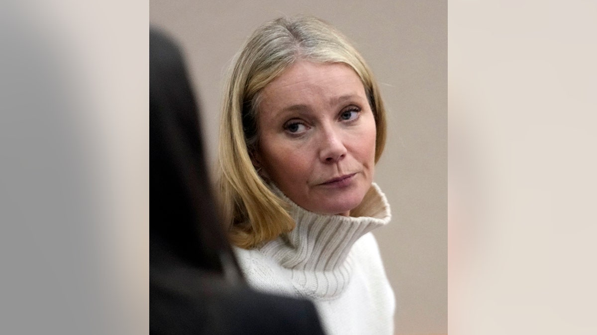 Gwyneth Paltrow looks frustrated in a light colored turtleneck as she looks back in court