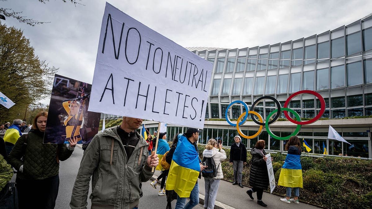 Ukrainians walk past the headquarters of International Olympic Committee (IOC) during a protest against the proposed IOC roadmap to organise the return to competition of Russian athletes under a neutral flag, provided that they have "not actively supported the war in Ukraine" in Lausanne on March 25, 2023. 