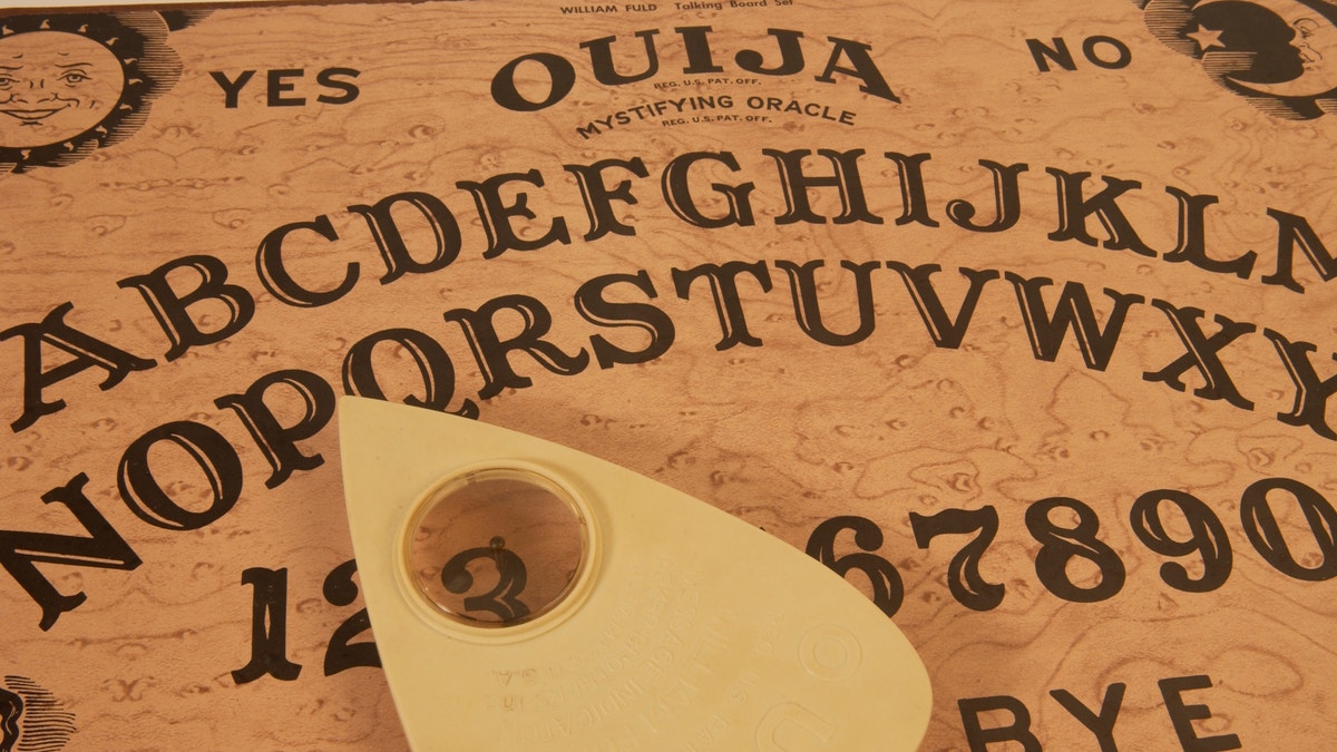 A Ouija board with the planchette hovering over the number three.