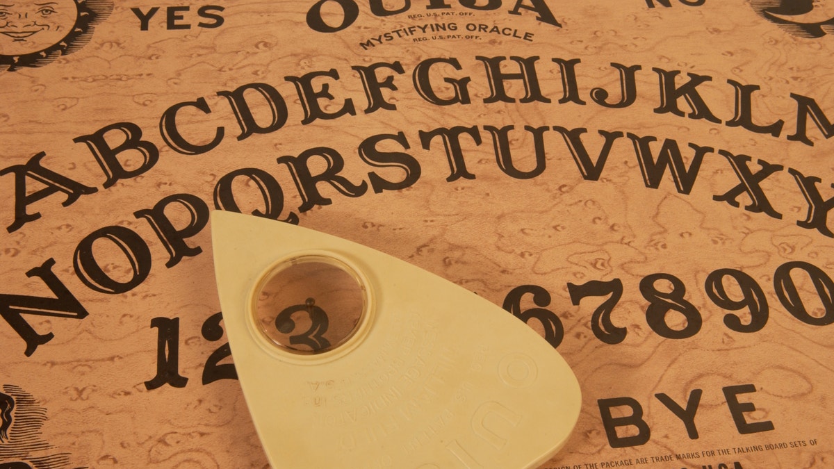 A Ouija board with the planchette hovering over the number three.