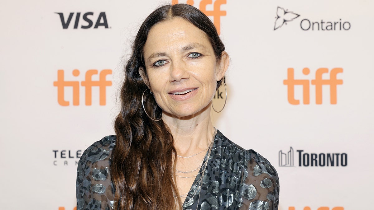 Justine Bateman smiles on the red carpet in Ontario in a printed top with transparent sleeves