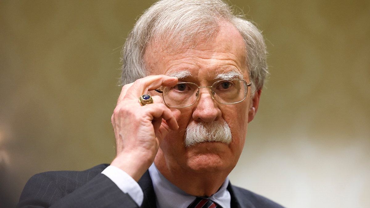 John Bolton fixes his glasses