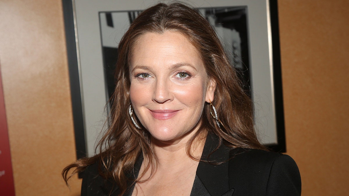 Drew Barrymore soft smiles in a black jacket with large hoop earrings in New York