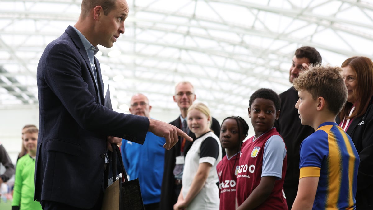 Prince William speaking with a group of young soccer players.