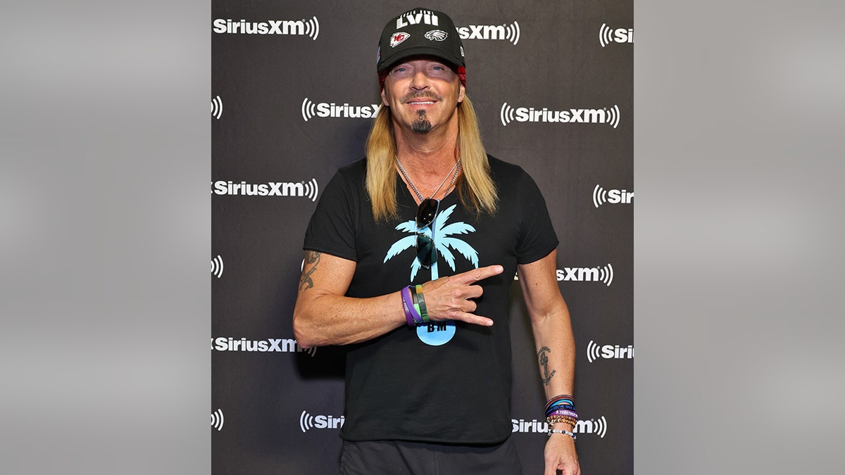 Bret Michaels in a black shirt with a turquoise palm tree and black Superbowl LVII hat at the SiriusXM event in Phoenix, Arizona