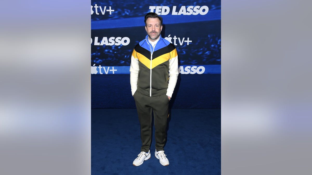 Jason Sudeikis standing on the blue carpet at the "Ted Lasso" premiere