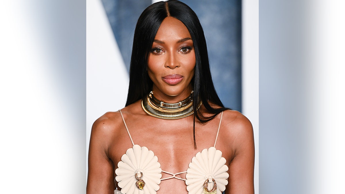 Naomi Campbell wears an ivory dress with scalloped breasted fabric with nipple piercings on the carpet for the Vanity Fair Oscar party