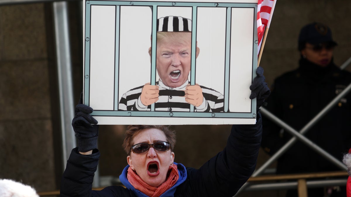 A person holds a sign outside the Manhattan Criminal Court referencing Trump's possible arrest.