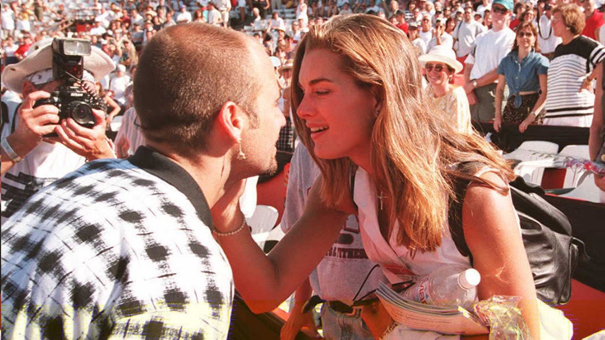 Brooke Shields holds Andre Agassi's face with her right hand as she leans in for a kiss after he won the Canadian Open