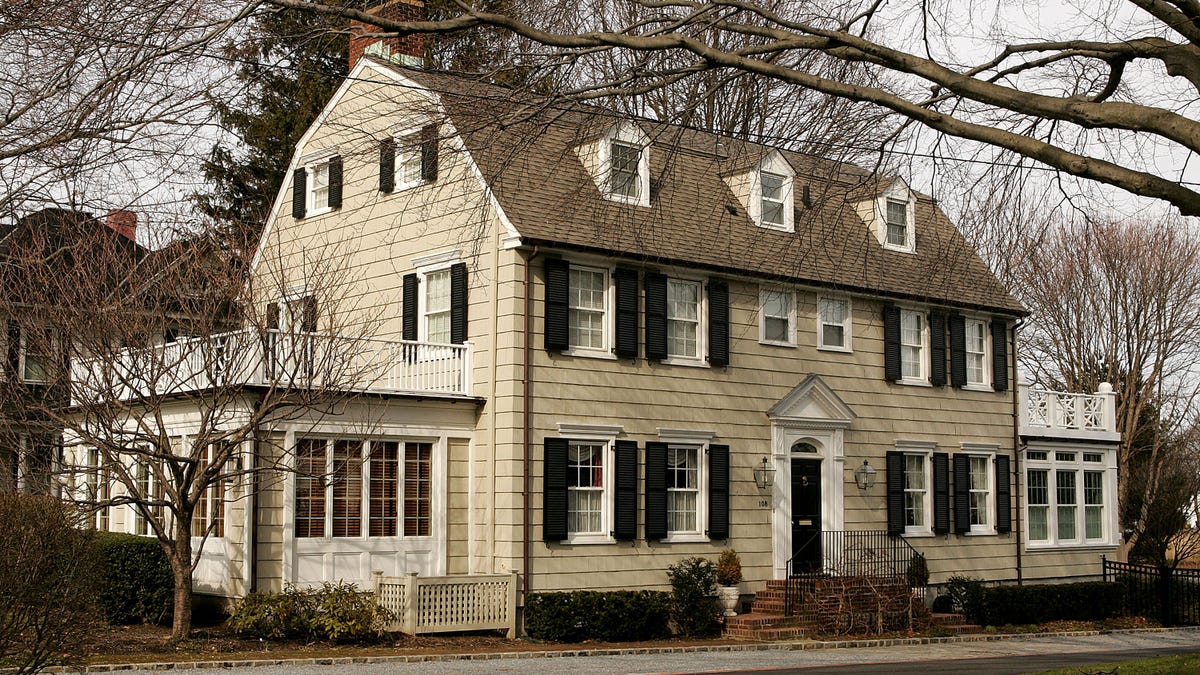 Amityville Horror House, colonial-style two-story home sits behind trees in fall photo