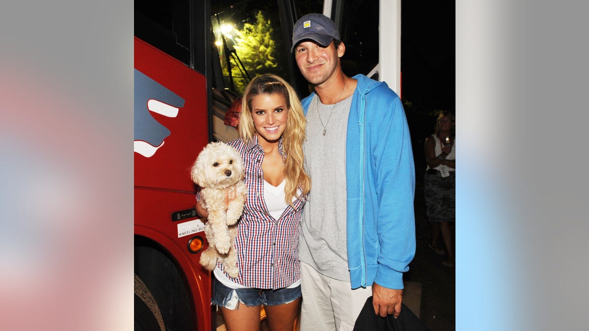 Jessica Simpson holds a dog while posing with Tony Romo