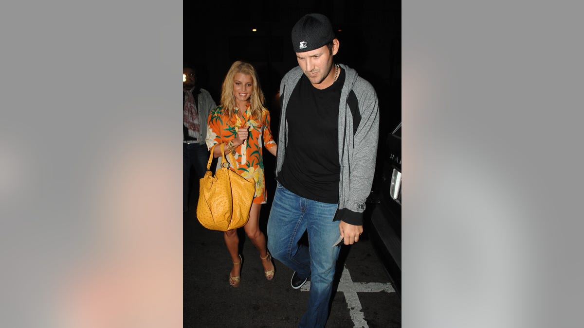 Jessica Simpson holding yellow purse as she walks with Tony Romo