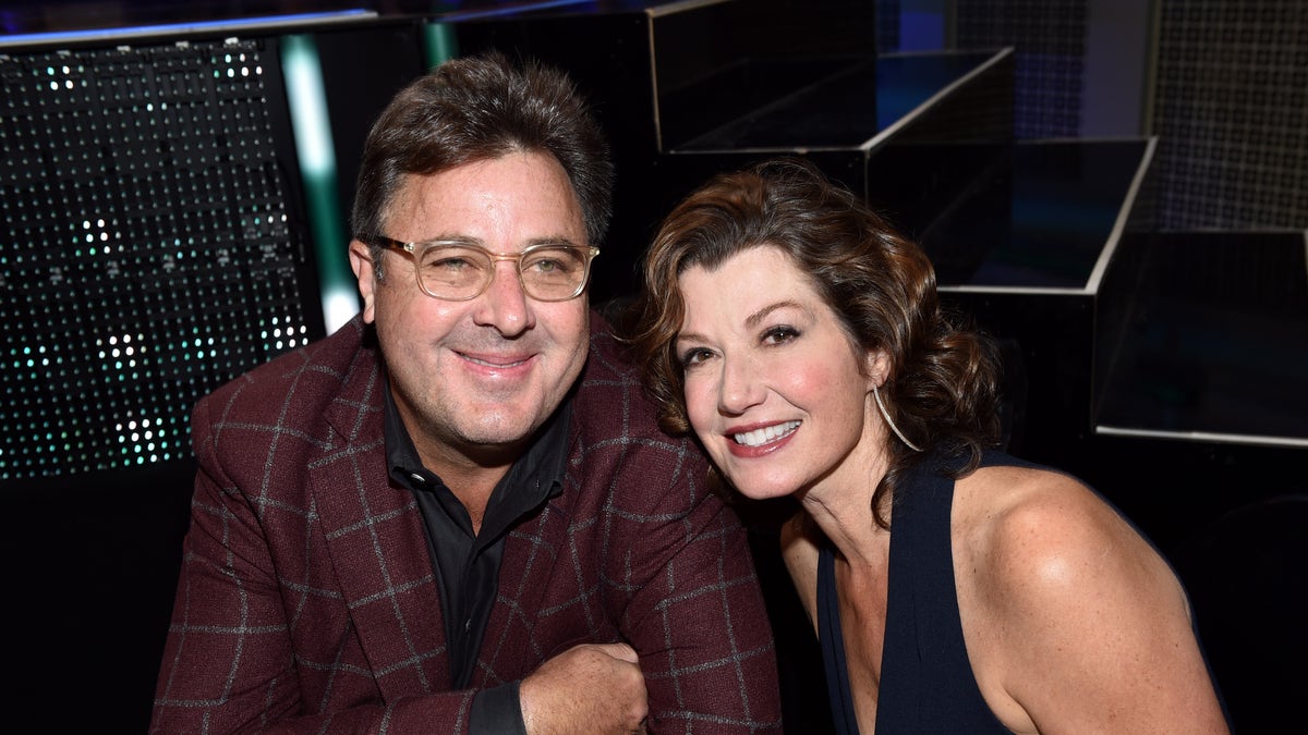 Vince Gill successful a burgundy plaid suit pinch Amy Grant leaning connected him, wearing a achromatic dress