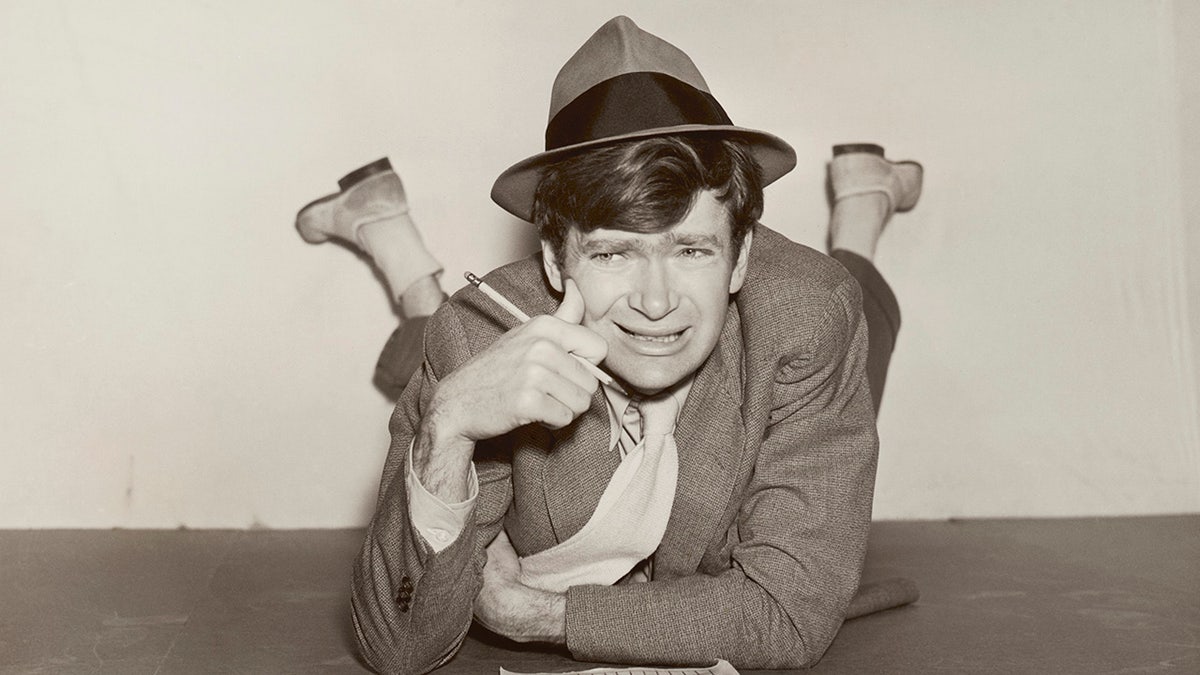 A young Buddy Ebsen looking at a crossword puzzle