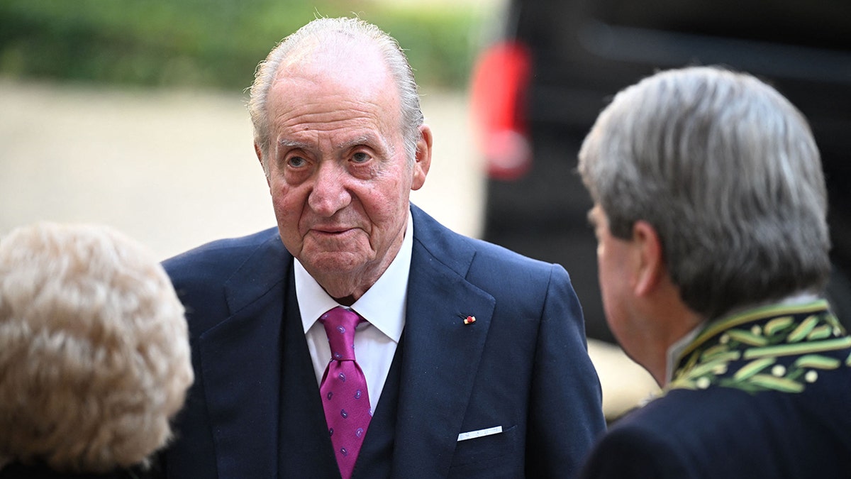 Spain's former King Juan Carlos I (C) is welcomed by Member of the French academy