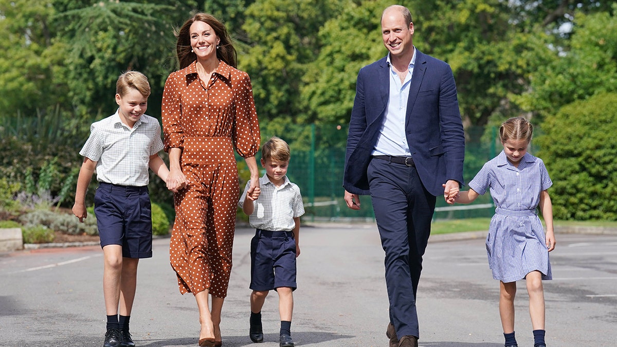 Prince William and Kate Middleton smiling to photographers as they walk their children to school
