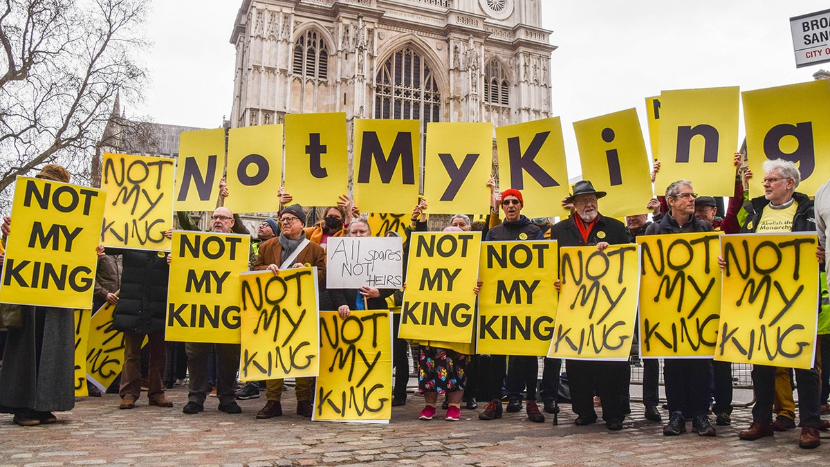 Anti-monarchy protestors holding yellow signs during Commonwealth Service