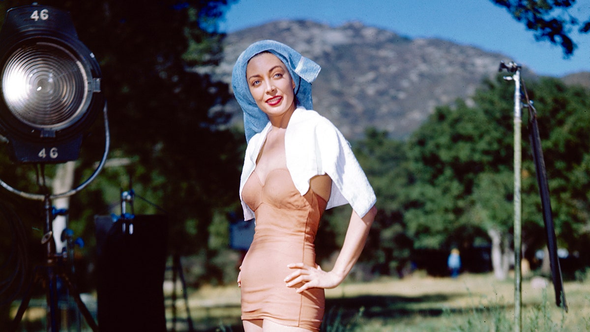 Marie Windsor wearing a peach swimsuit with a blue swimming cap