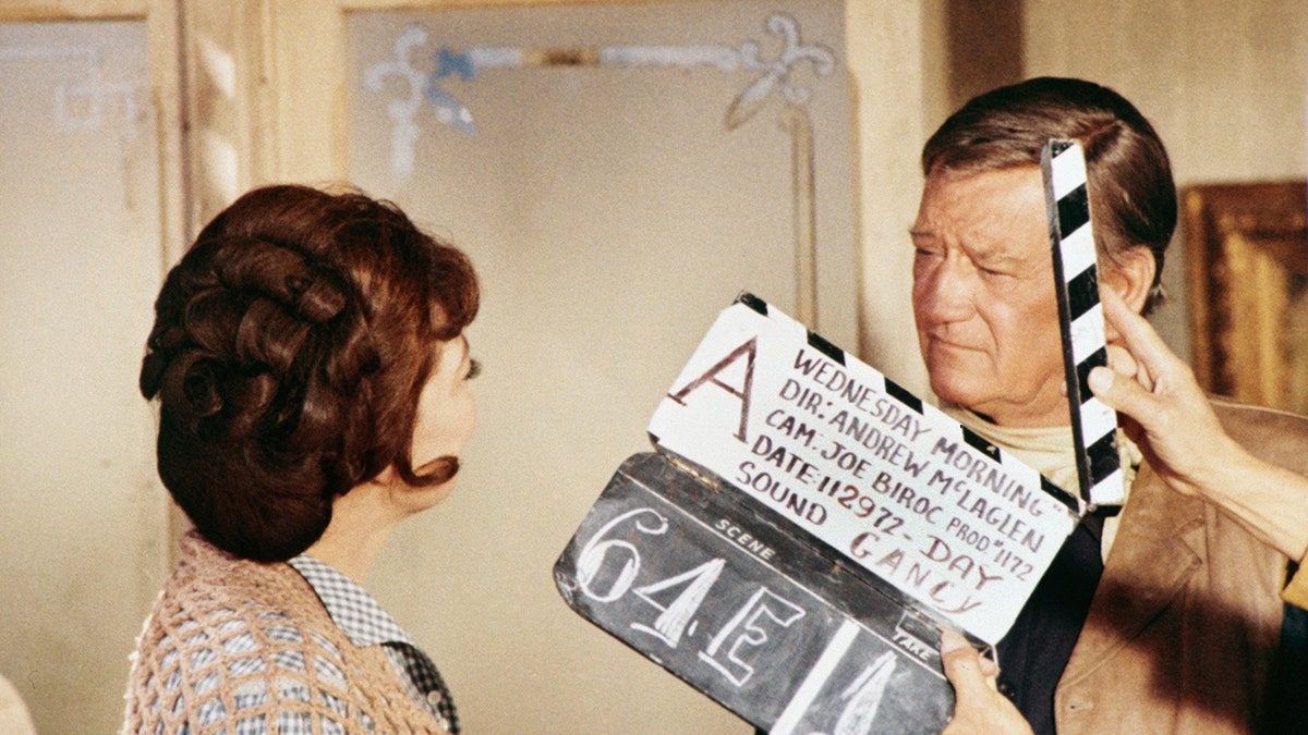 Marie Windsor and John Wayne filming a scene
