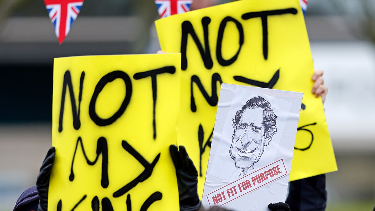 A close-up of yellow signs from protestors protesting King Charles and the British monarchy