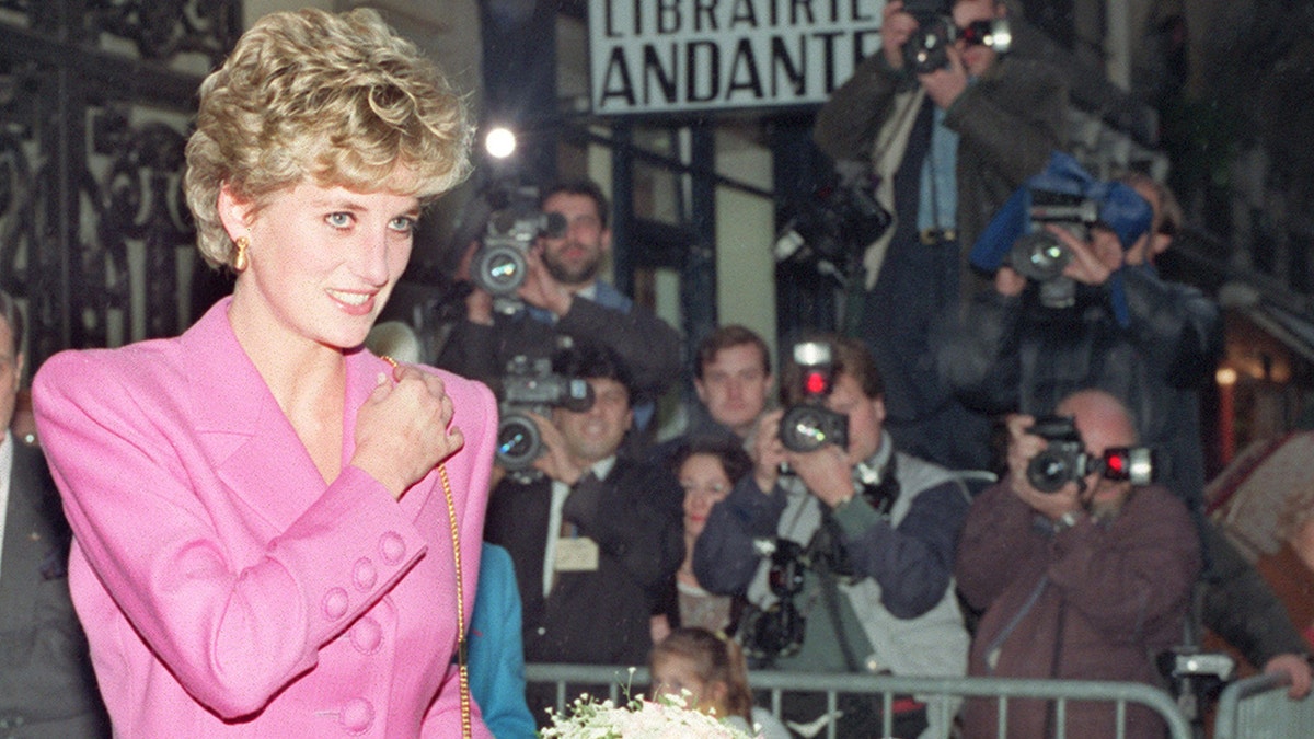 Princess Diana wearing a pink suit while looking away from paparazzi