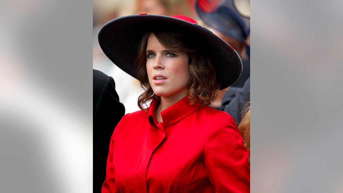 A close-up of Princess Eugenie wearing a red coat and a matching hat