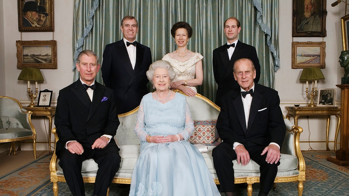 Queen Elizabeth in a light blue dress sitting and smiling next to her husband and children